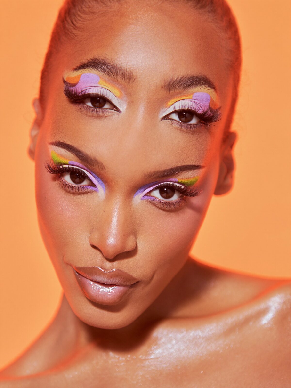 Woman with bold tangerine and lilac graphic eye makeup